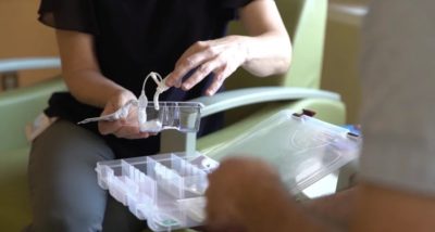 A health care worker opens a portable tracheotomy kit.