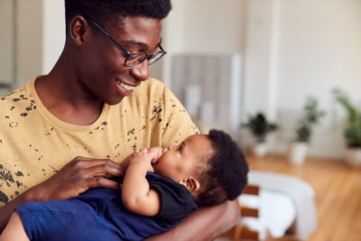 Loving Father Holding Newborn Baby At Home In Loft Apartment